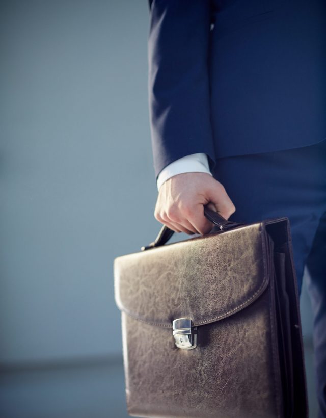 Leather briefcase Vertical cropped image of a businessperson carrying a leather briefcase isolated on grey